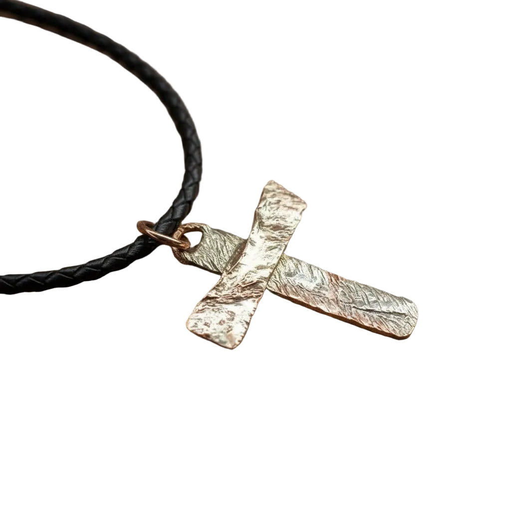 Gold cross pendant on a black cord against a gray background