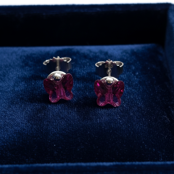 Fuchsia butterfly studs on navy velvet tray