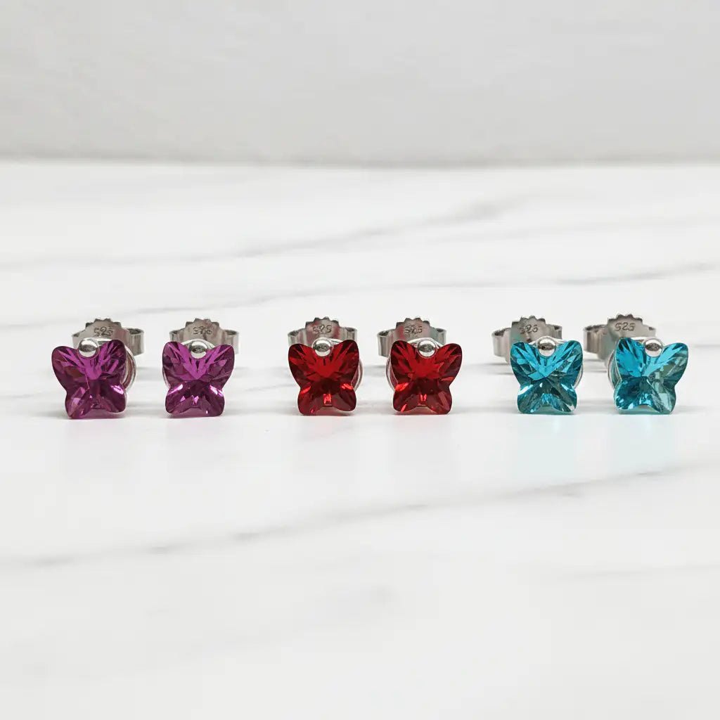 Butterfly stud earrings in all three colors on marble
