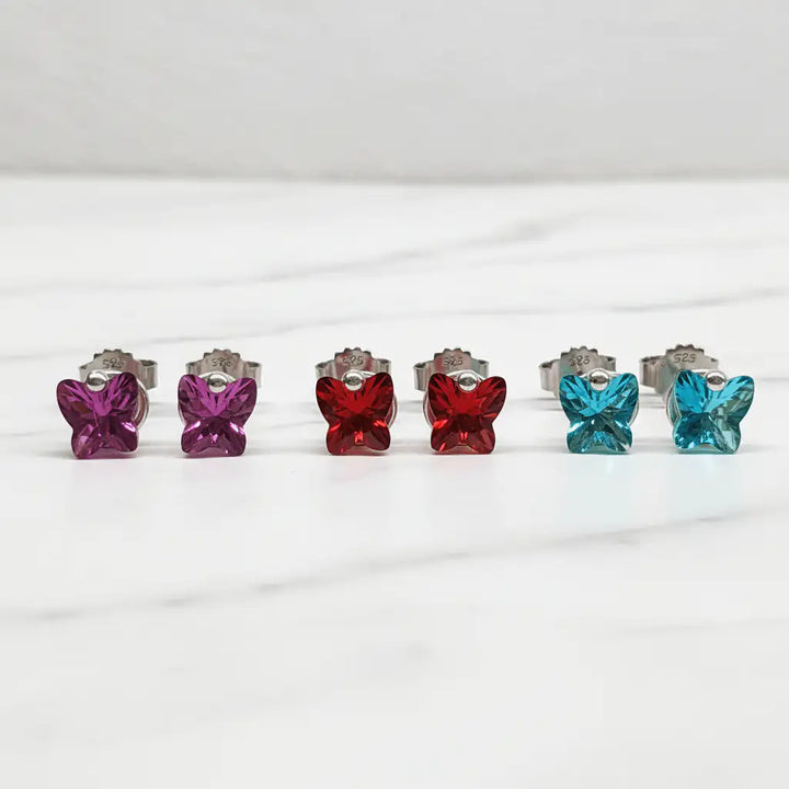 Butterfly stud earrings in all three colors on marble