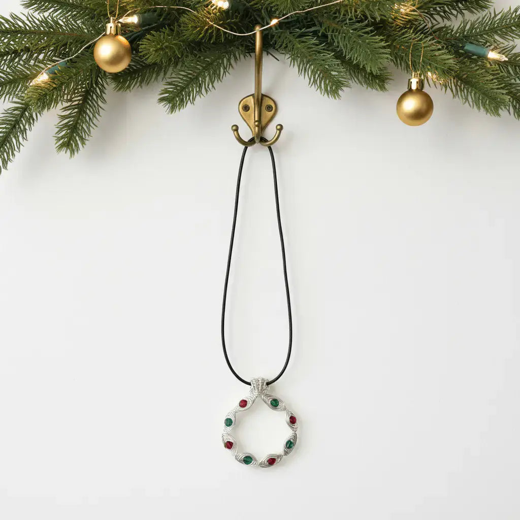 Christmas wreath necklace hanging on brass hook with garland