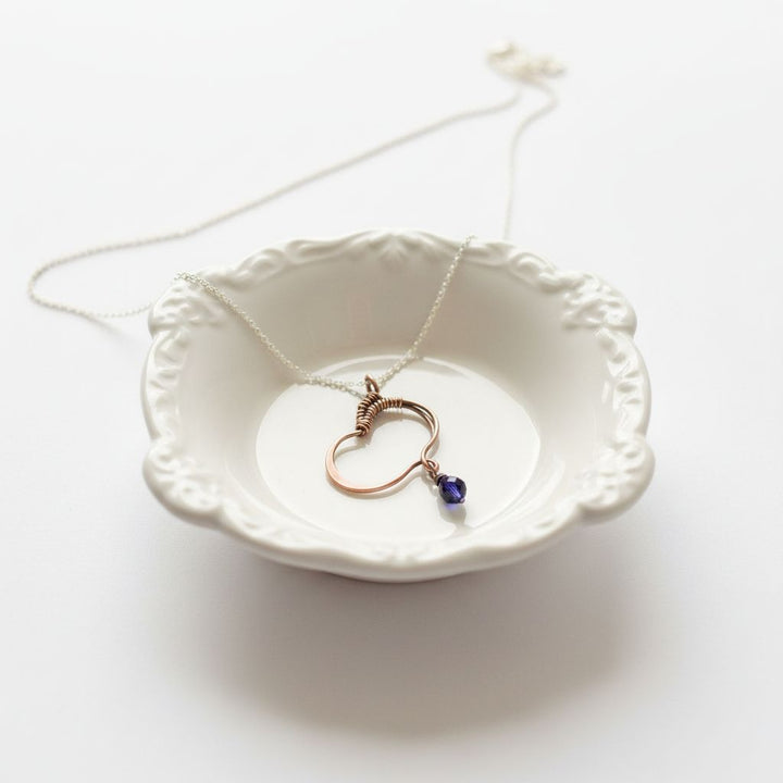 Hammered Copper Butterfly Wing Child Abuse Survivor Necklace on a delicate chain in a decorative dish.