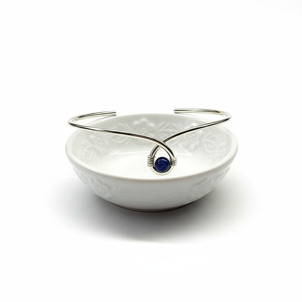 Silver Blue Bead Child Abuse Awareness Ribbon Bangle displayed in a decorative white bowl.
