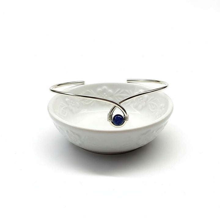 Silver Blue Bead Child Abuse Awareness Ribbon Bangle displayed in a decorative white bowl.