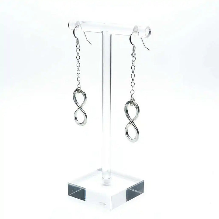 Sterling Silver Hammer Patterned Infinity Earrings displayed on a clear stand, showcasing their elegant design.