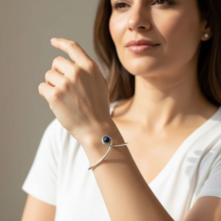 Silver Blue Bead Child Abuse Awareness Ribbon Bangle worn on a woman's wrist, showcasing its unique design and blue sandstone bead.