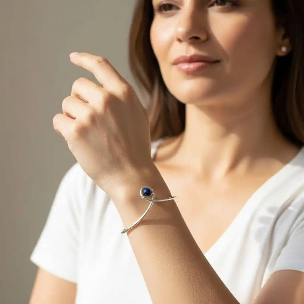 Silver Blue Bead Child Abuse Awareness Ribbon Bangle worn on a woman's wrist, showcasing its unique design and blue sandstone bead.