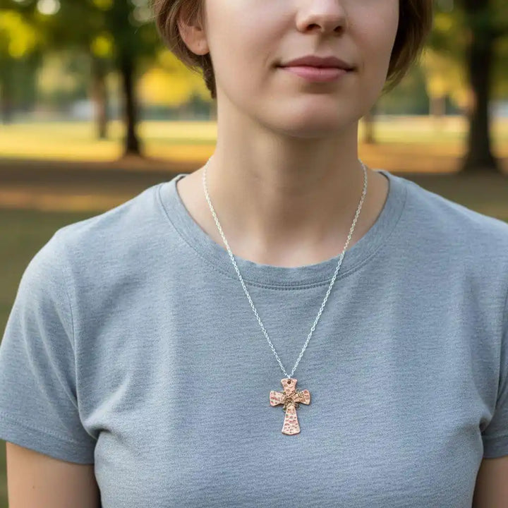 Chained Hammered Copper Cross Necklace For Him Or Her worn by a person in a gray t-shirt outdoors.