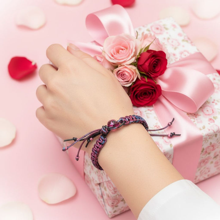 Close-up of a hand wearing a Macrame Tie-Dye Leather Crystal Bracelet next to a gift box with flowers.
