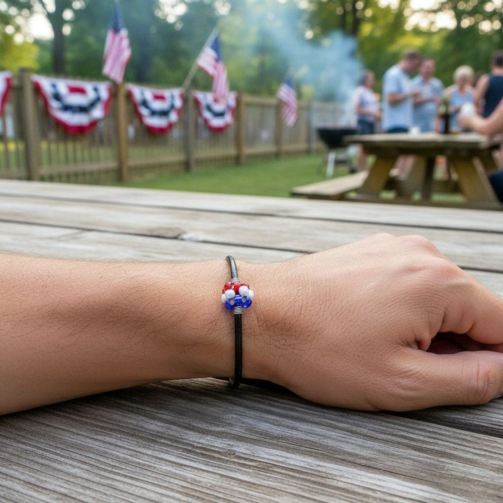 Patriotic Red White Blue Beaded Bead Leather Bracelet worn on wrist with American flags in background.