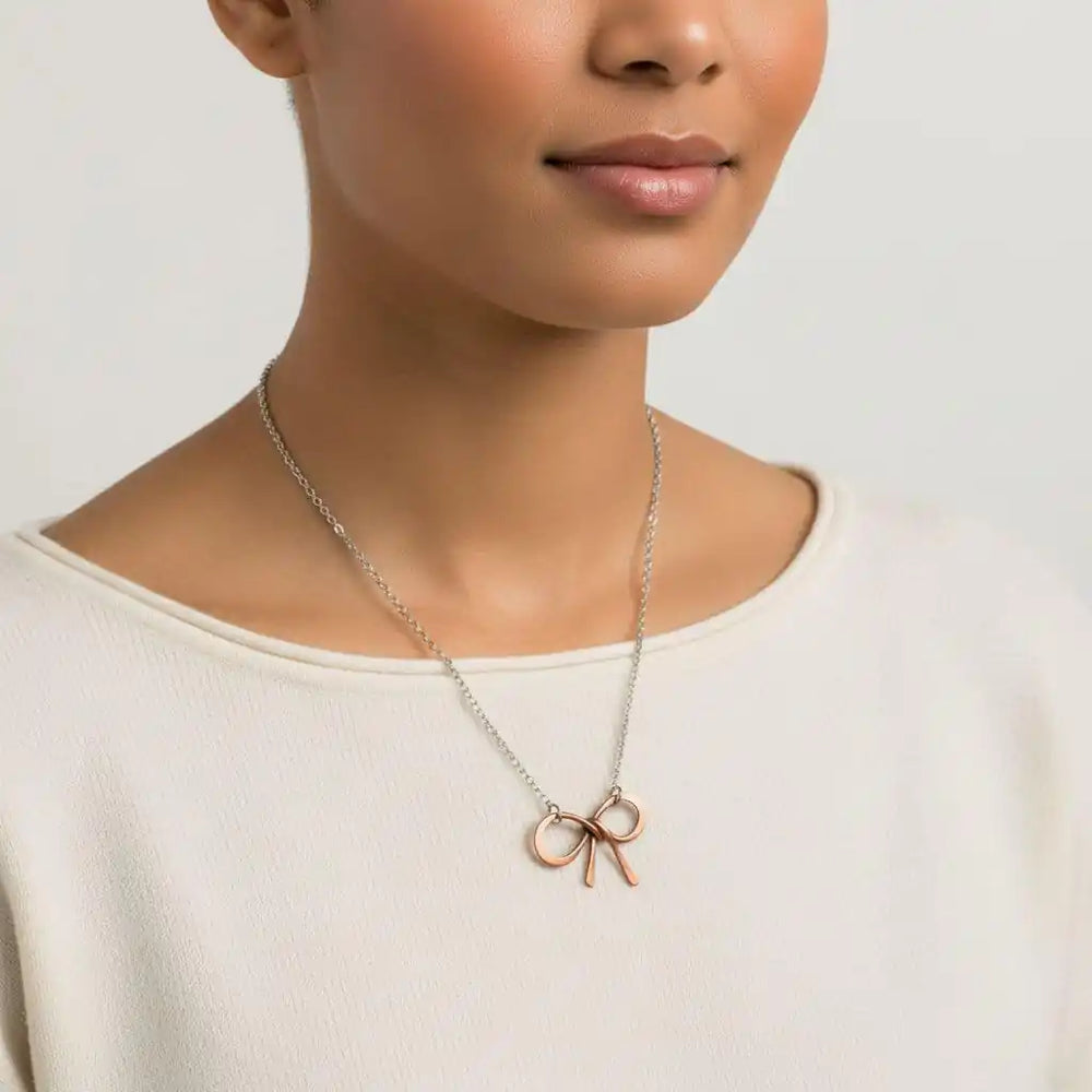 Model wearing a Wire Wrapped Copper Bow Tie Silver Chain Necklace with a hand-sculpted copper pendant.