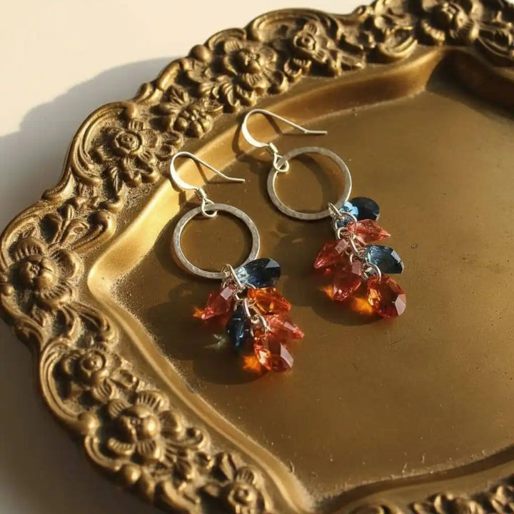 Silver Circle Multi Color Crystal Drop Dangle Earrings displayed on an ornate golden plate, showcasing vibrant crystals.