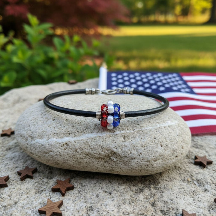 Patriotic Red White Blue Beaded Bead Leather Bracelet on a stone with American flag in the background.