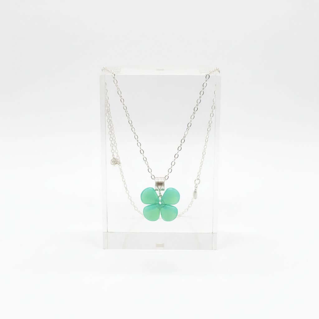 Mint green beaded clover necklace displayed in a clear stand, featuring Czech glass beads and sterling silver.