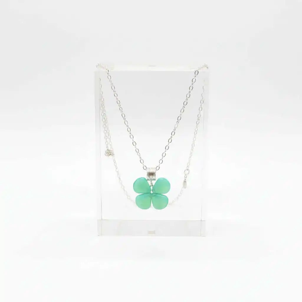 Mint green beaded clover necklace displayed in a clear stand, featuring Czech glass beads and sterling silver.