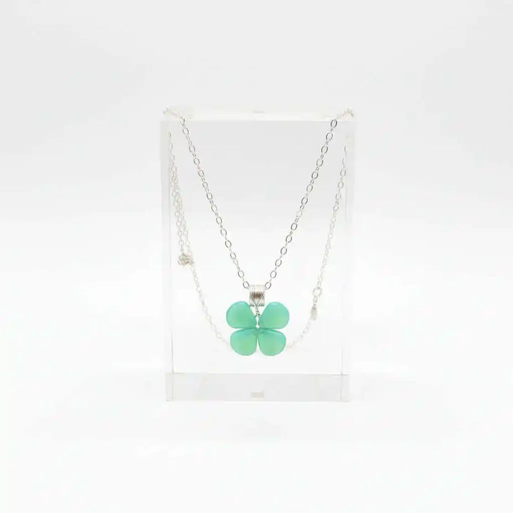 Mint green beaded clover necklace displayed in a clear stand, featuring Czech glass beads and sterling silver.