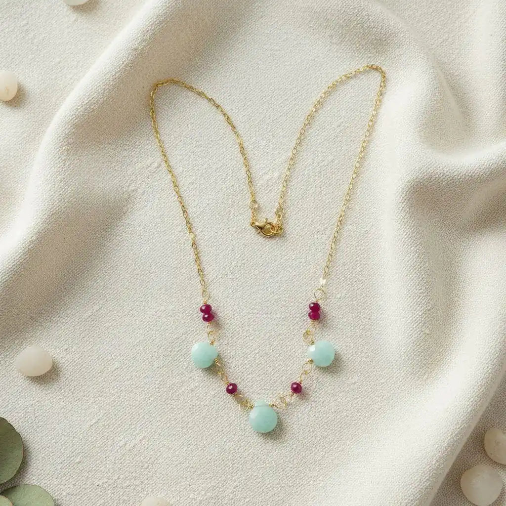 Dainty Gold Chain Mint and Hot Pink Gemstone Necklace on a soft fabric background with mint and hot pink gemstones.