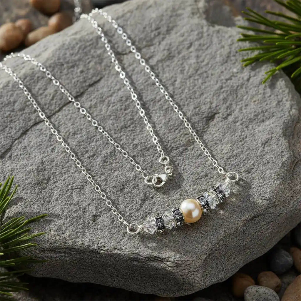 Silver Swarovski Crystal Pearl Bar Bridal Necklace displayed on a stone with greenery.