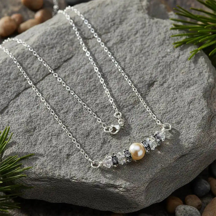 Silver Swarovski Crystal Pearl Bar Bridal Necklace displayed on a stone with greenery.