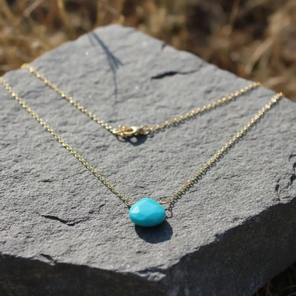 Gold Filled Aqua Jade Wire Wrap Gemstone Drop Necklace placed on a textured stone background.