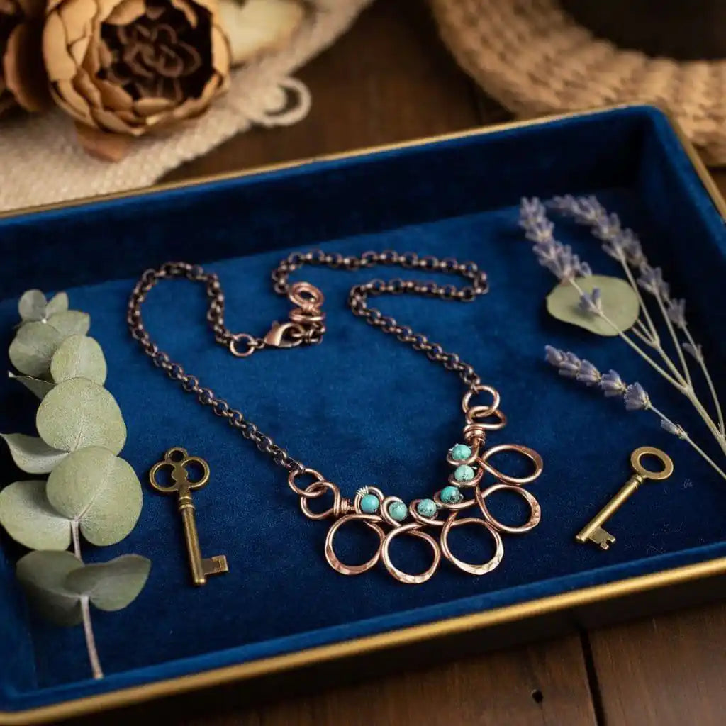 Seen on Ashley Liao Copper Turquoise Wire Wrapped Necklace displayed on a blue velvet tray with decorative elements.