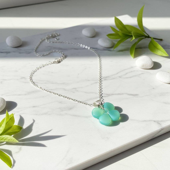 Mint green beaded clover necklace featuring Czech glass beads on a silver chain, set on marble background.