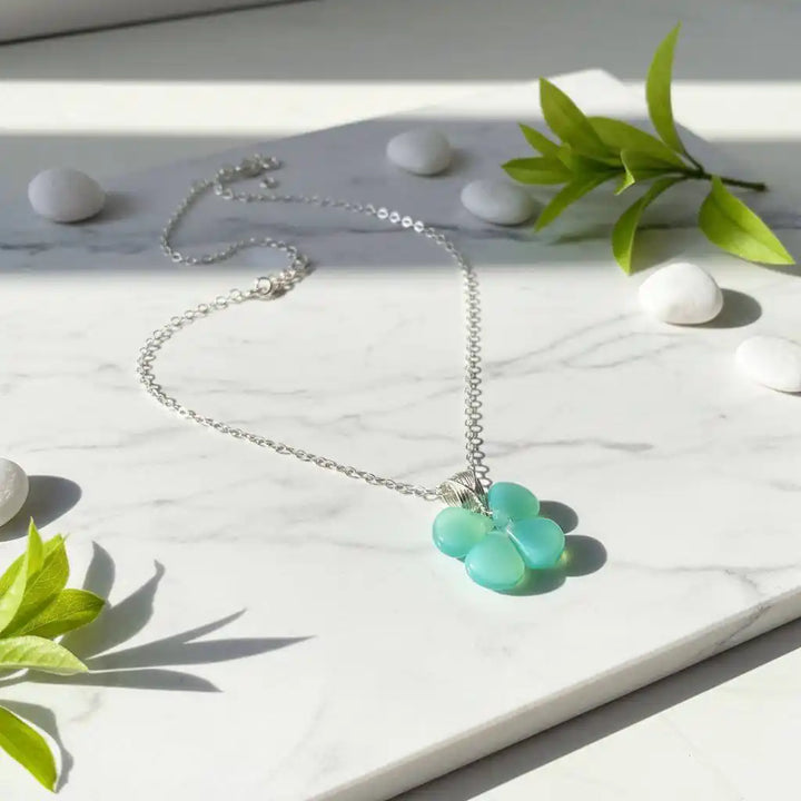 Mint green beaded clover necklace featuring Czech glass beads on a silver chain, set on marble background.