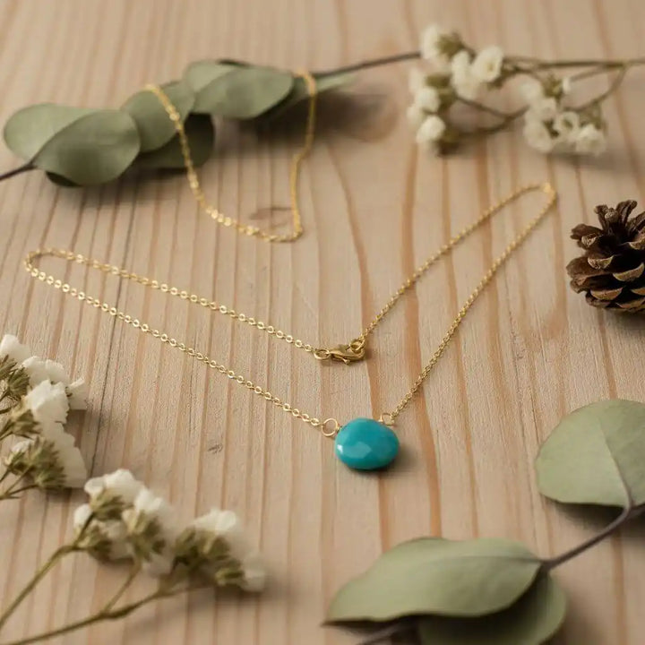 Gold Filled Aqua Jade Wire Wrap Gemstone Drop Necklace showcased on wooden surface with flowers and pinecone.