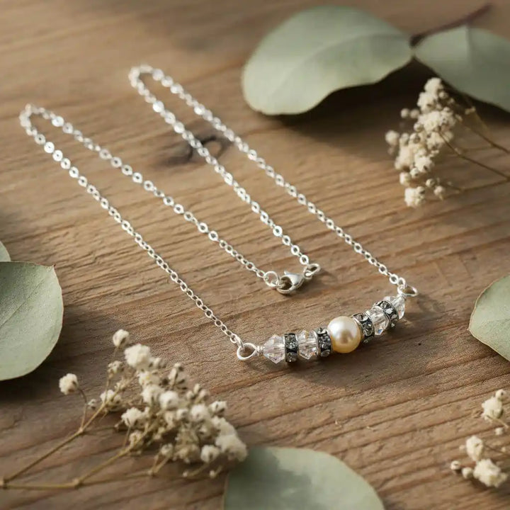 Silver Swarovski Crystal Pearl Bar Bridal Necklace on wooden surface with greenery and flowers.