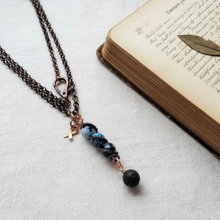 Child Abuse Awareness Agate Necklace With Lava Rock Bead featuring copper spiral pendant and blue agate beads.