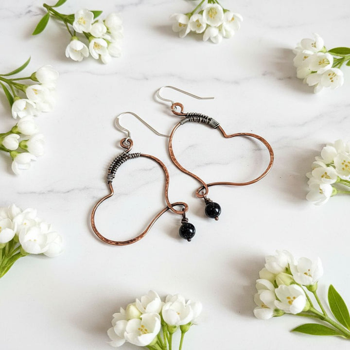 Sculpted Copper Butterfly Wing Abuse Survivor Earrings with black Swarovski crystal dangles on a marble background.