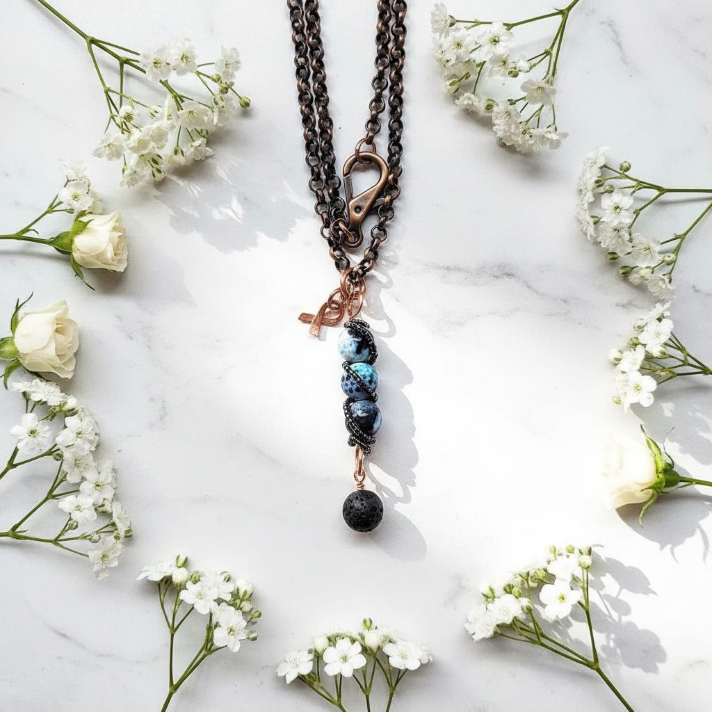 Child Abuse Awareness Agate Necklace With Lava Rock Bead displayed among white flowers.
