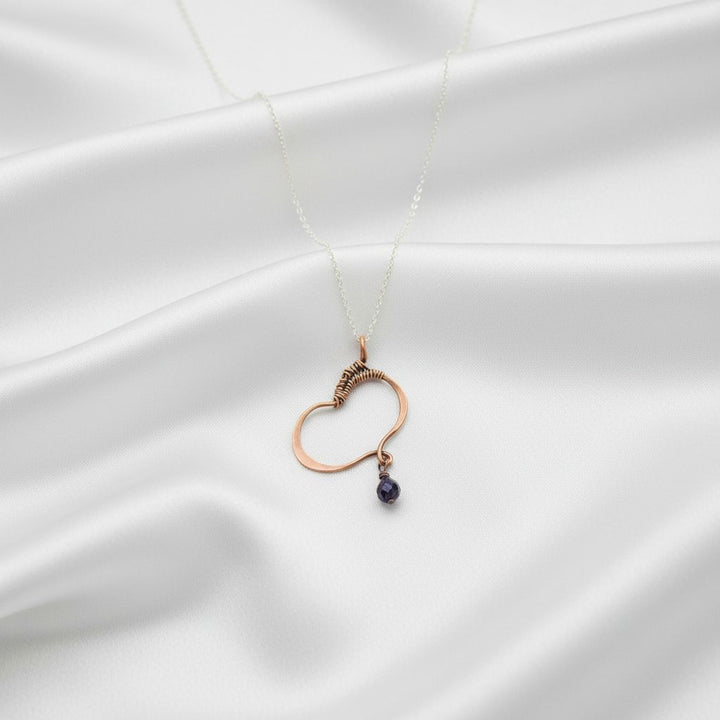 Hammered Copper Butterfly Wing Child Abuse Survivor Necklace with purple crystal pendant on a satin background.