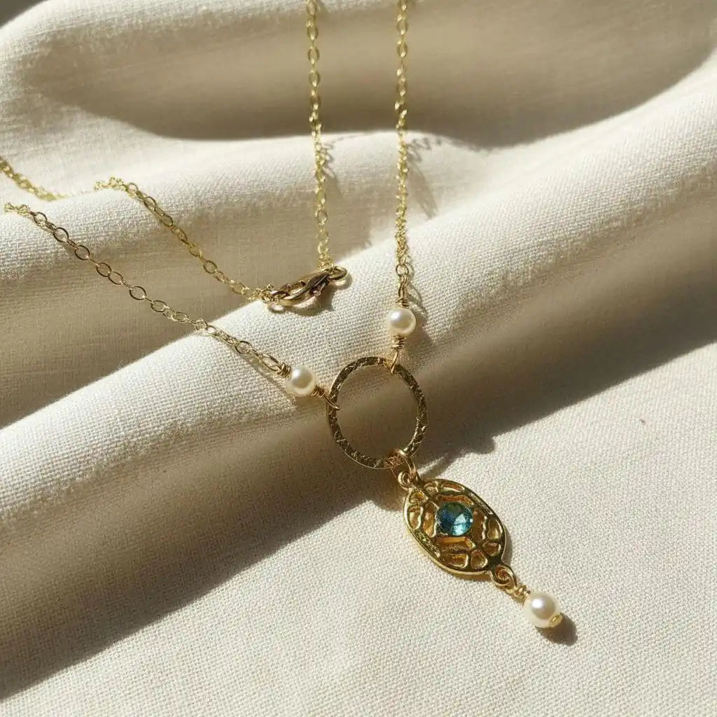 14 K Gold-Filled Hammered Open Circle Filigree Necklace with gemstone and pearls on a soft fabric background.