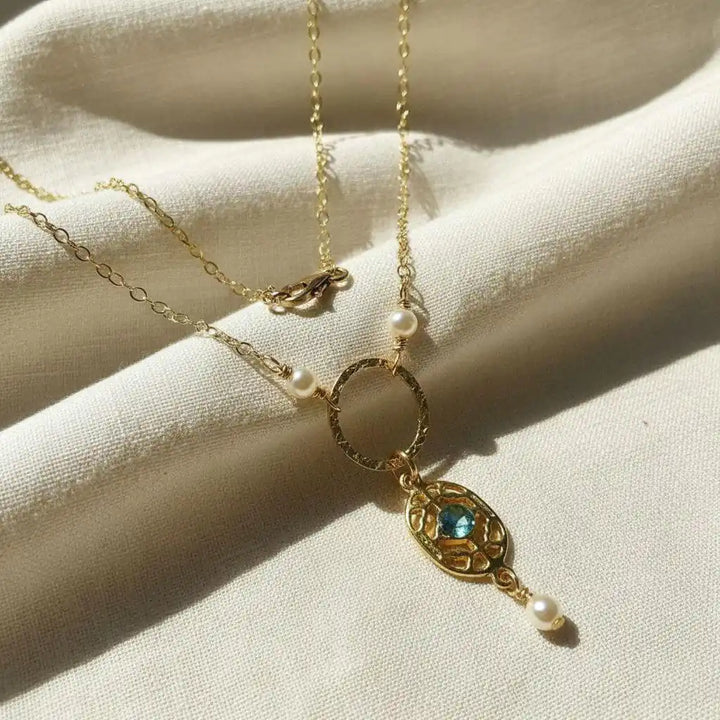 14 K Gold-Filled Hammered Open Circle Filigree Necklace with gemstone and pearls on a soft fabric background.