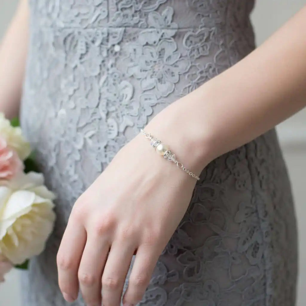 Silver Swarovski Crystal Pearl Bar Bridal Bracelet worn on a hand with a floral bouquet, showcasing elegance and style.