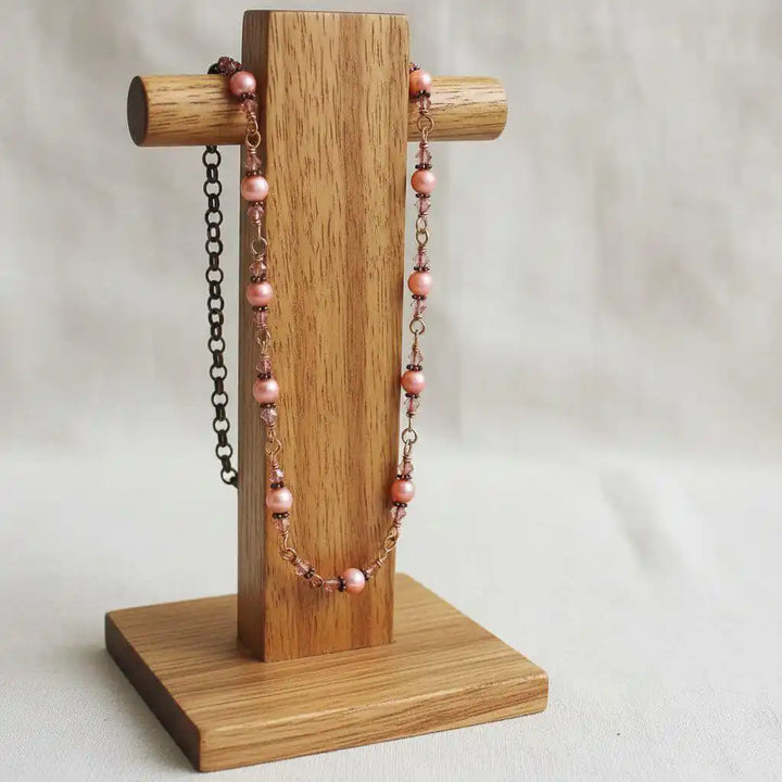 24-Inch Copper Peach Pearl Crystal Wire Wrapped Necklace displayed on a wooden jewelry stand.