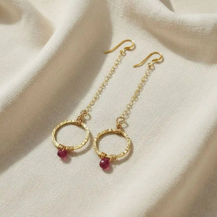 Gold Filled Wrapped Pink Chalcedony Open Circle Earrings hanging on a neutral fabric.