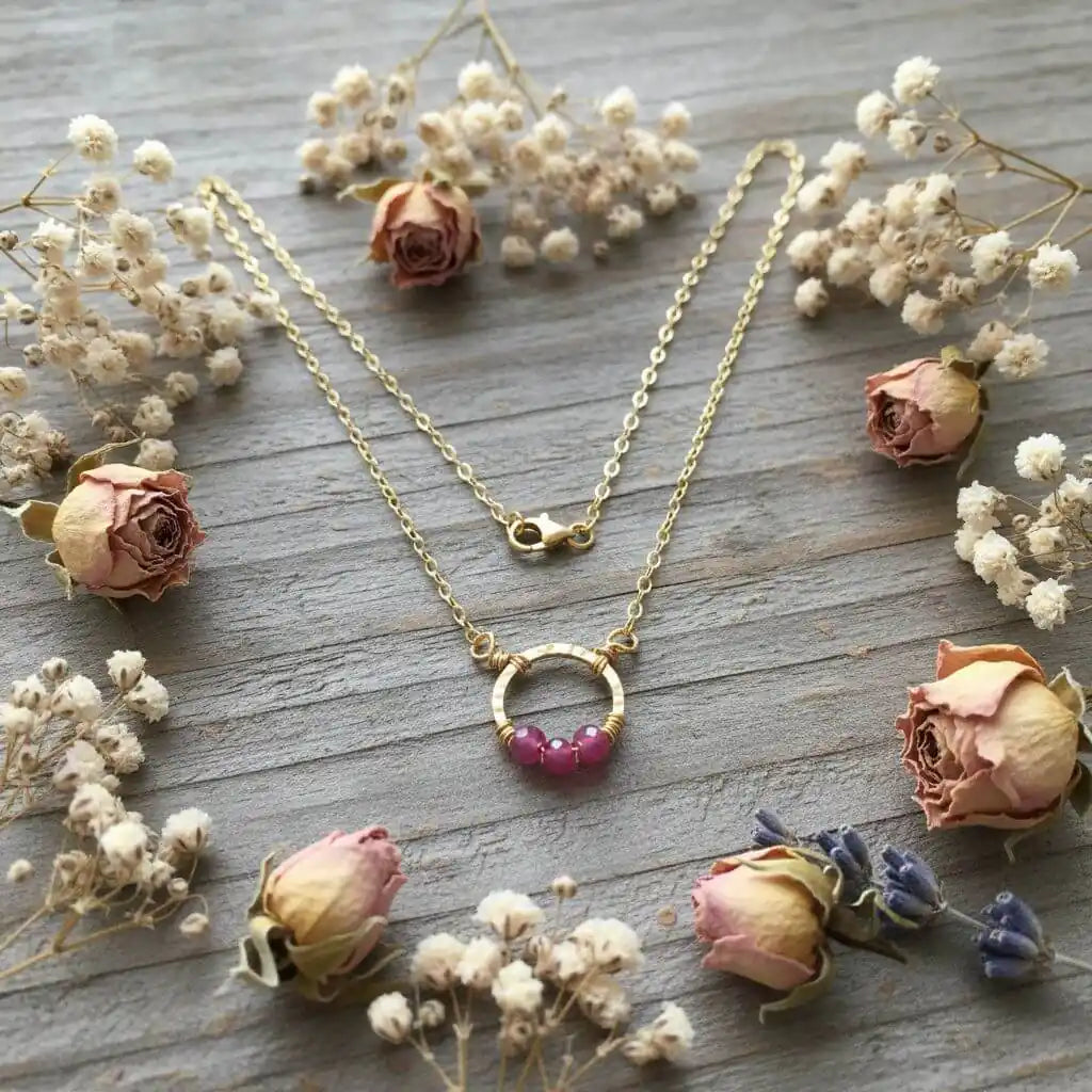 Gold Filled Pink Chalcedony Open Circle Necklace surrounded by dried roses and flowers.