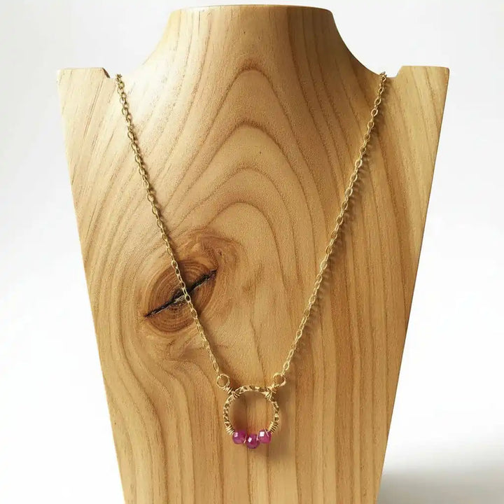 Gold Filled Pink Chalcedony Open Circle Necklace displayed on a wooden bust with pink beads.