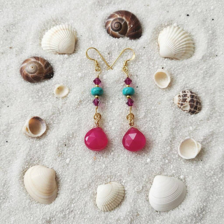 Gold Filled Wire Wrapped Pink Turquoise Gemstone Earrings with pink chalcedony and turquoise heishi beads on sandy background.