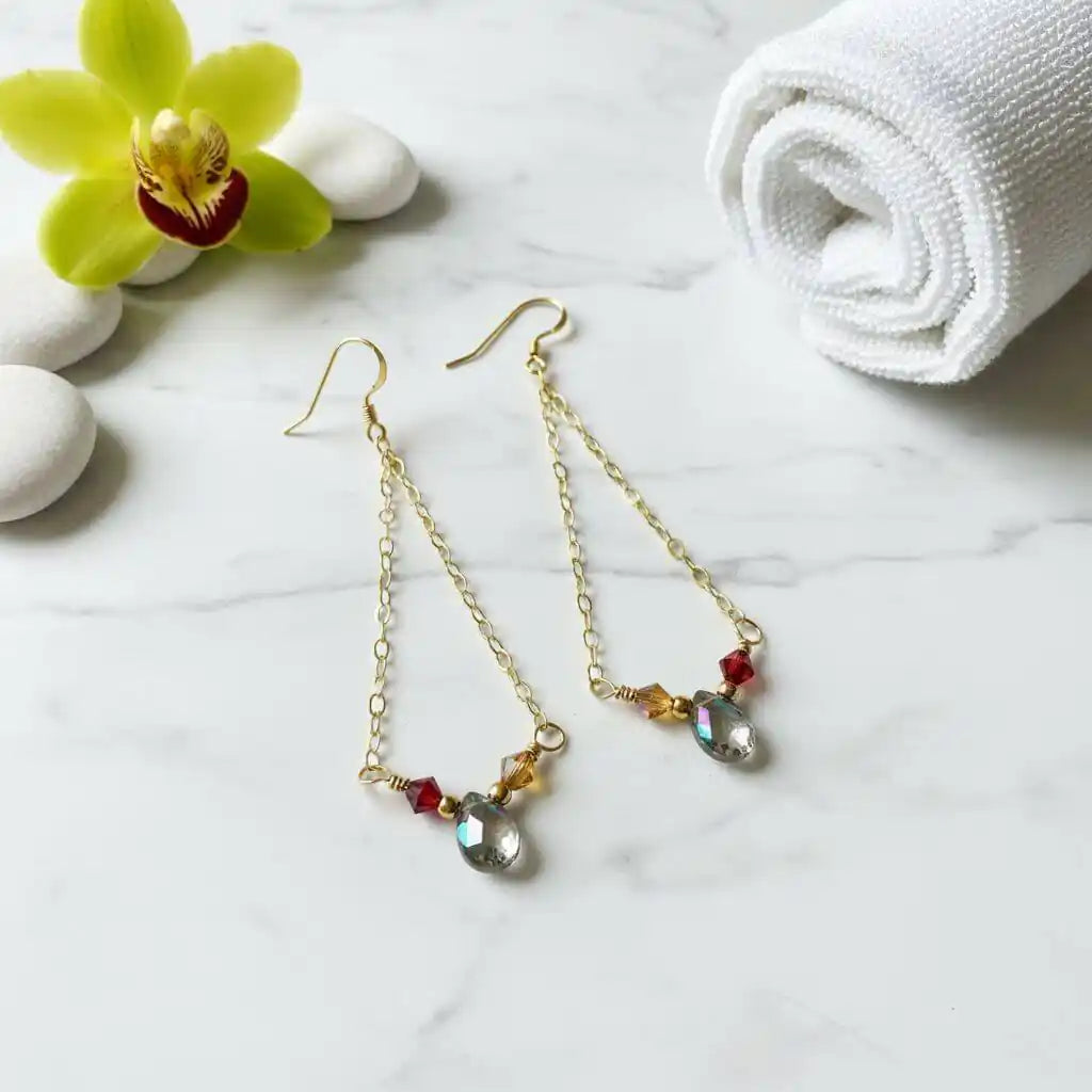 Mystic Rainbow Quartz Drop Gold Filled Earrings with sparkling gemstones and gold-filled components on a marble surface.