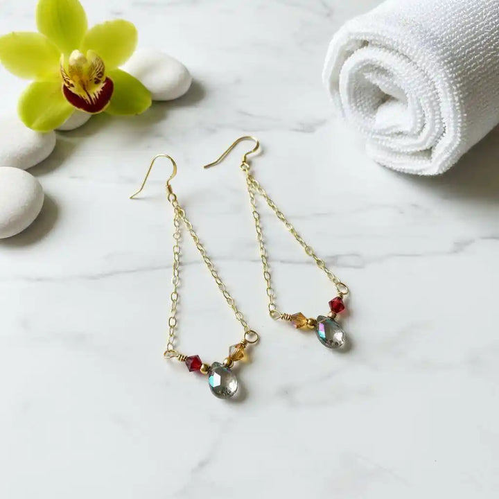 Mystic Rainbow Quartz Drop Gold Filled Earrings with sparkling gemstones and gold-filled components on a marble surface.