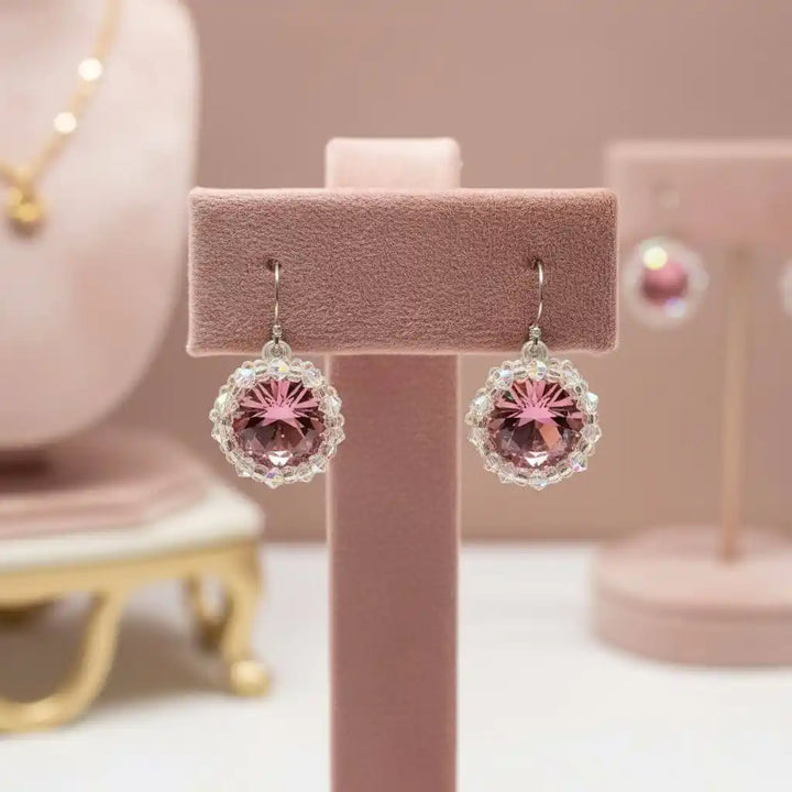Handmade Beaded Bezel Pink Crystal Halo Earrings displayed on a pink earring stand with sparkling Swarovski crystals.