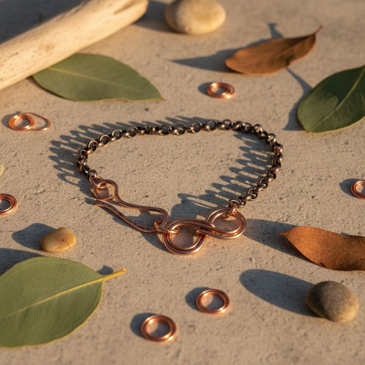 Wire Sculpted Copper Double Infinity Chain Bracelet displayed on a natural surface with leaves and stones.