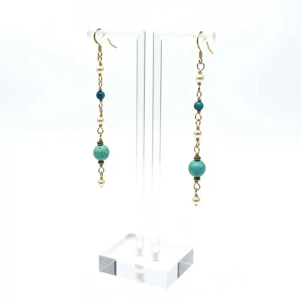 Long 14 K Gold Filled Turquoise Pearl Earrings hanging on a display stand showcasing elegant design and colors.