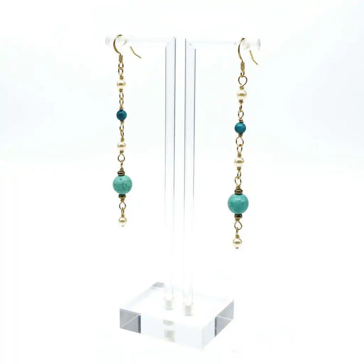 Long 14 K Gold Filled Turquoise Pearl Earrings hanging on a display stand showcasing elegant design and colors.