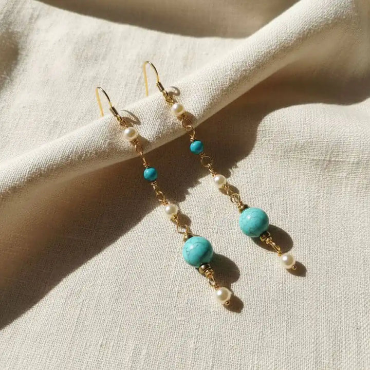 Long 14 K Gold Filled Turquoise Pearl Earrings showcasing turquoise stones and Swarovski pearls on a soft fabric backdrop.