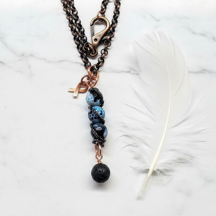 Child Abuse Awareness Agate Necklace With Lava Rock Bead featuring blue agate beads, copper spiral pendant, and lava rock charm.