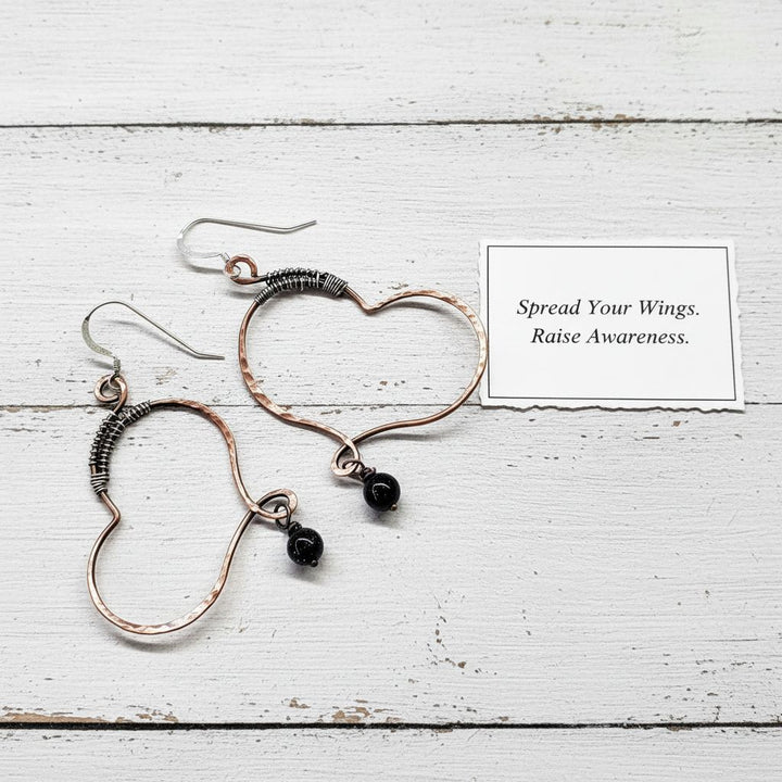 Sculpted Copper Butterfly Wing Abuse Survivor Earrings with black Swarovski crystal dangles on white background.